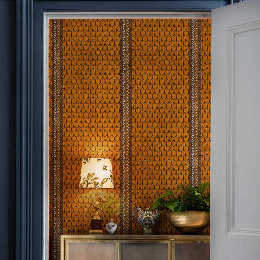 Oranje behang met Ardmore Narina-patroon van Cole and Son in een stijlvol interieur met decoratieve accessoires.
