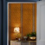 Oranje behang met Ardmore Narina-patroon van Cole and Son in een stijlvol interieur met decoratieve accessoires.