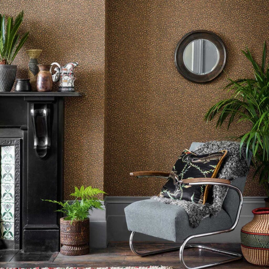 Interieurhoek met Cole and Son Ardmore Senzo Spot behang, een grijze fauteuil, planten en decoratieve accessoires.