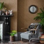 Interieurhoek met Cole and Son Ardmore Senzo Spot behang, een grijze fauteuil, planten en decoratieve accessoires.