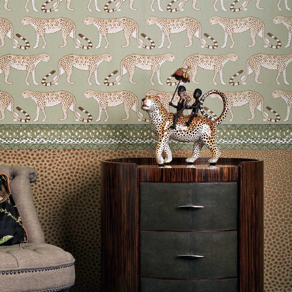 Behang met luipaardmotief uit de Cole and Son Ardmore Senzo Spot collectie, gecombineerd met een decoratief beeldje op een houten kastje.