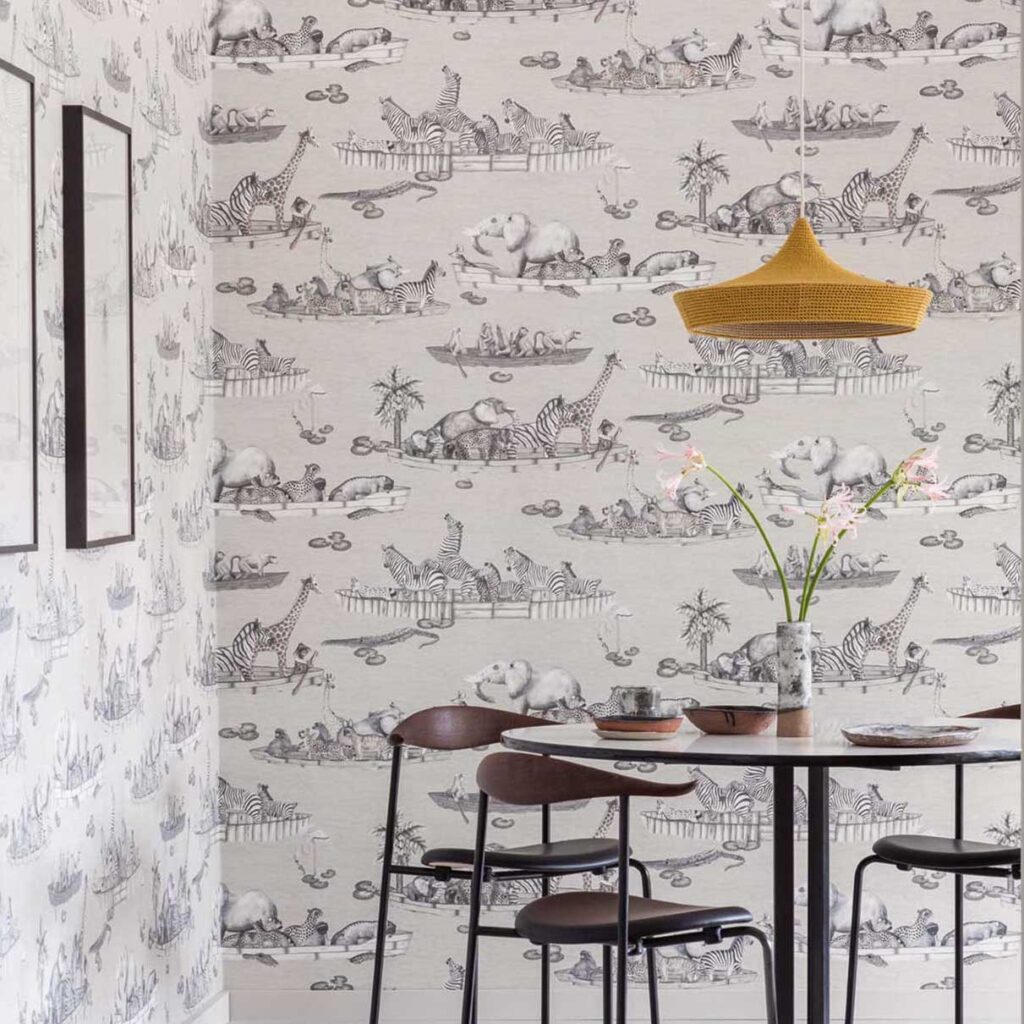 Behang met zwart-witte tekeningen van Afrikaanse dieren in boten uit de Cole and Son Ardmore Zambezi collectie, in een modern ingerichte eetkamer.