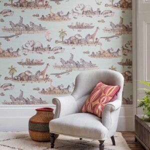 Grijze fauteuil met sierkussen voor een muur met Cole & Son Ardmore Zambezi behang met Afrikaanse dieren in boten.