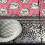 Zwart-wit Cole and Son Ardmore Zulu Border behang met dierenmotieven op een roze achtergrond, gecombineerd met grafische patronen en een moderne stoel op de voorgrond.