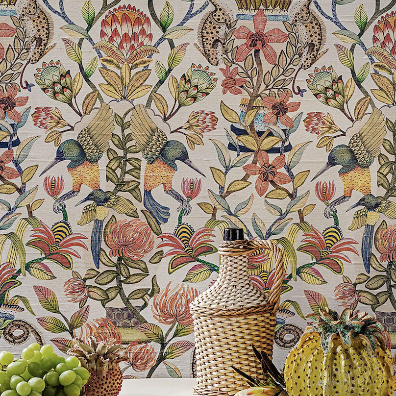 Gedetailleerd en kleurrijk behang van Cole and Son met exotische bloemen, vogels en vlechtwerkdecoratie op de voorgrond.