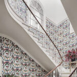 Trap in een hal met kleurrijk Cole & Son Ardmore Jabula Nene-behang en sierlijke witte leuning.