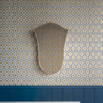 Wand met Cole and Son Hicks Hexagon behang in geometrisch patroon met spiegel die hetzelfde patroon weerspiegelt.