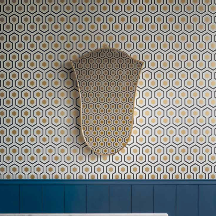 Wand met Cole and Son Hicks Hexagon behang in geometrisch patroon met spiegel die hetzelfde patroon weerspiegelt.