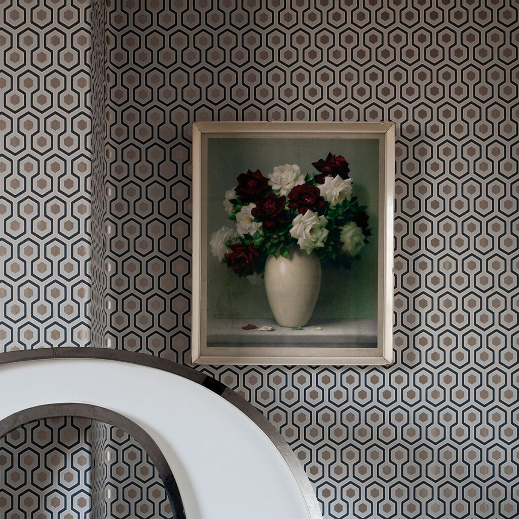 Vaas met bloemen aan de muur met Cole and Son Hicks Hexagon behang op de achtergrond.