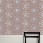 Decoratief Cole & Son Fioretti behang met symmetrisch patroon in zachte pasteltinten boven een witte lambrisering en een zwarte stoel.