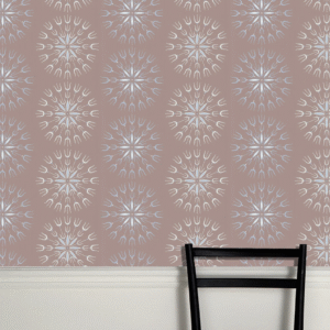 Decoratief Cole & Son Fioretti behang met symmetrisch patroon in zachte pasteltinten boven een witte lambrisering en een zwarte stoel.