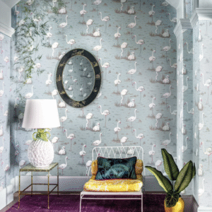 Interieur met Cole and Son flamingobehang, een witte lamp in ananasvorm en een kleurrijke stoel met sierkussen.