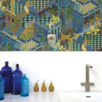 Wand met kleurrijk Cole and Son Miami behang in blauw, gecombineerd met een minimalistisch wit keukenblad met blauwe flessen, peren en een modern kraanarmatuur.