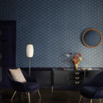 Donkerblauwe kamer met Cole and Son Feather Fan behang, moderne meubels en een gouden vaas met bloemen.