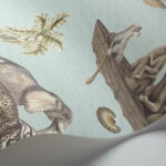 Behang uit de Cole and Son Sambezi Ardmore collectie met illustraties van dieren, waaronder een olifant, apen in een kano en tropische planten op een lichtblauwe achtergrond.