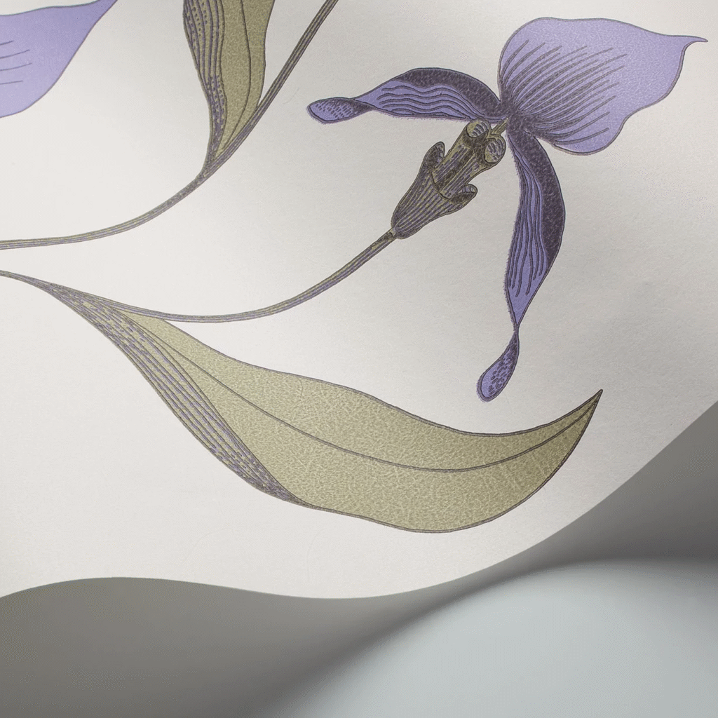 Detail van het Cole and Son Orchid behang met een gestileerde paarse orchidee en groene bladeren op een lichtgekleurde achtergrond.