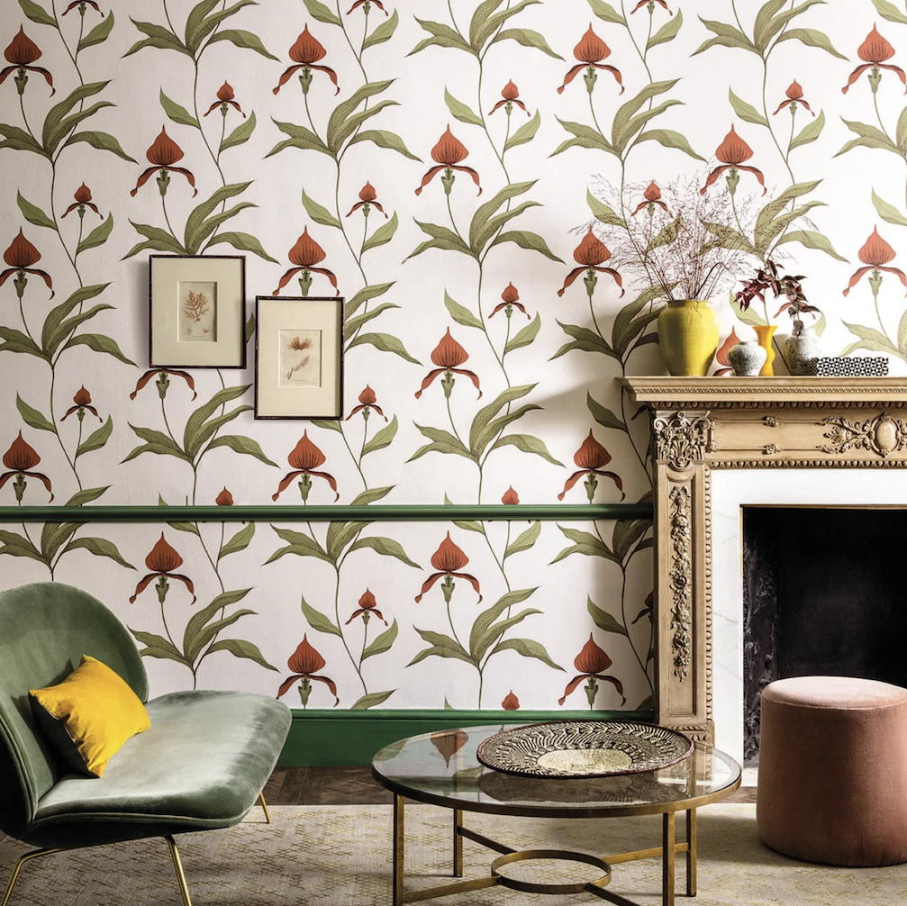 Stijlvol interieur met Cole & Son Orchid behang in een bloemenpatroon, gecombineerd met een klassieke schouw en moderne meubels.
