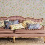 Vintage bank met decoratieve kussens voor Cole & Son behang met kolibries en bloempatronen.