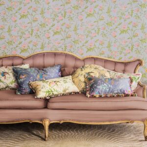 Vintage bank met decoratieve kussens voor Cole & Son behang met kolibries en bloempatronen.