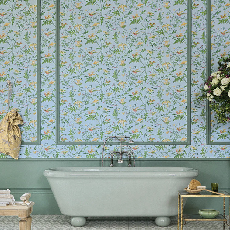Klassieke badkamer met een vrijstaand bad en Cole & Son Hummingbirds-behang met bloemen en kolibries op een lichtblauwe achtergrond.