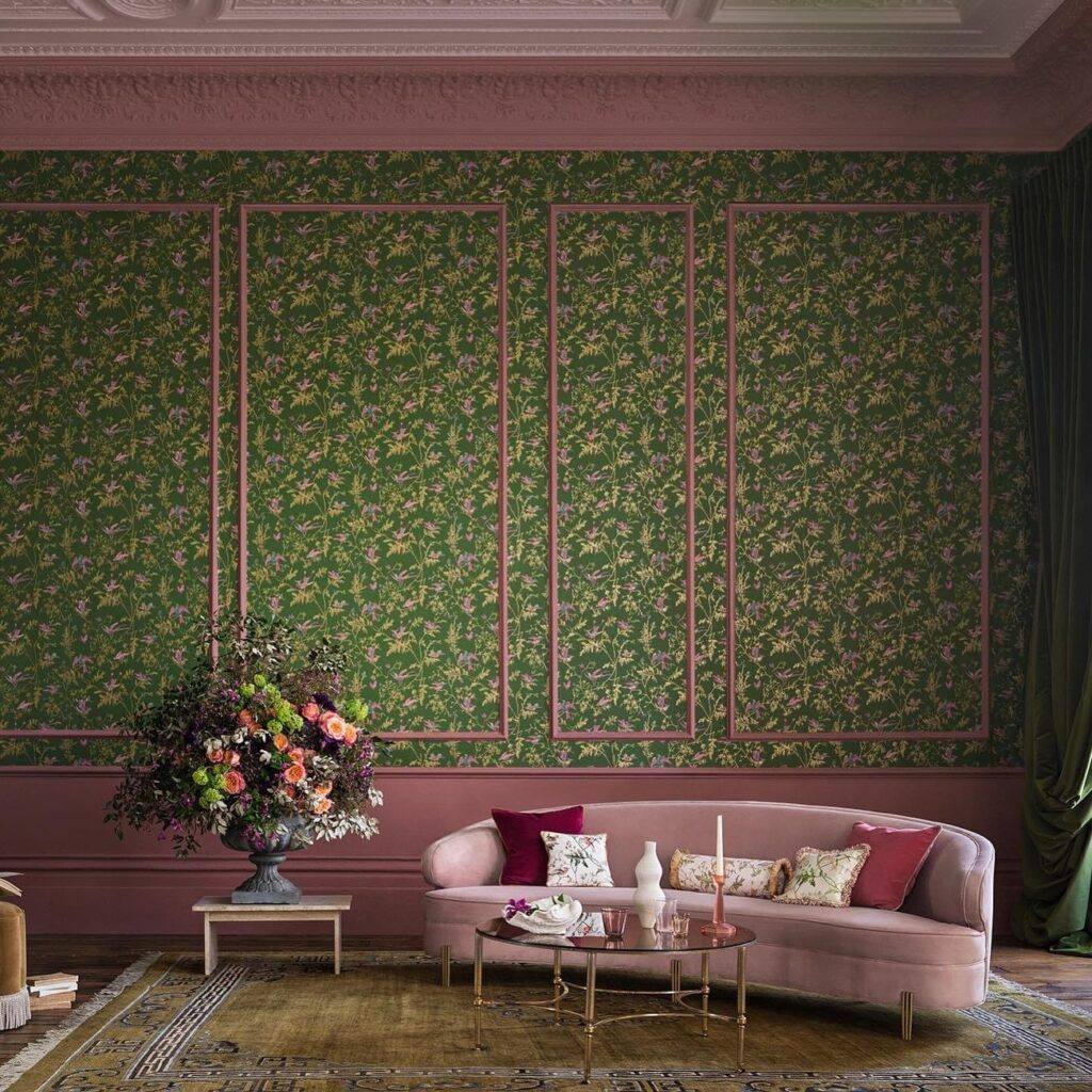 Sfeervolle woonkamer met Cole & Son Hummingbirds-behang in groen en roze, een roze fluwelen bank en een groot bloemstuk.