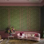 Sfeervolle woonkamer met Cole & Son Hummingbirds-behang in groen en roze, een roze fluwelen bank en een groot bloemstuk.