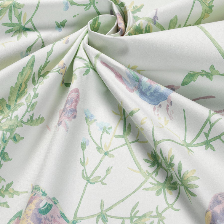 Detail van Cole & Son-stof ‘Hummingbirds’ met een pastelkleurig patroon van kolibries en groene planten op katoenen doek.