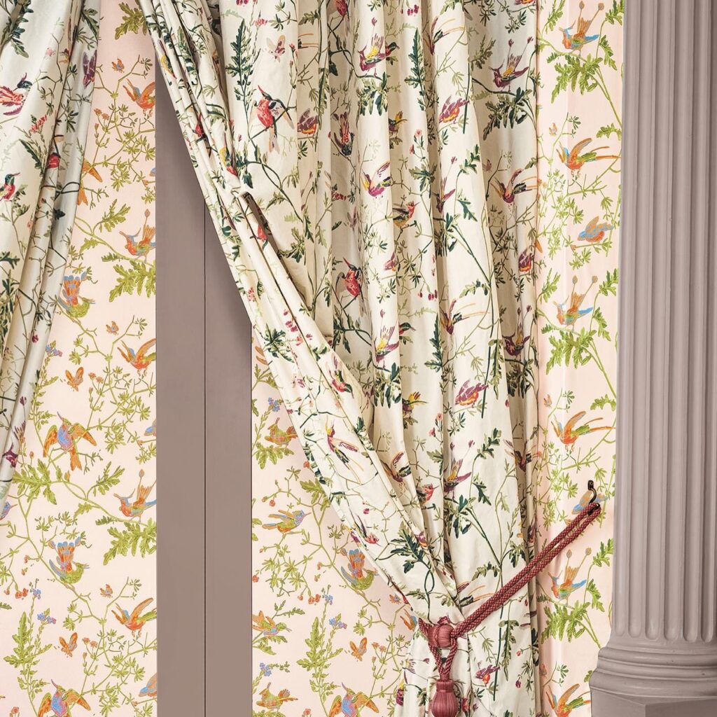 Crèmekleurige gordijnen en bijpassend behang met een kleurrijk kolibrimotief van Cole & Son.