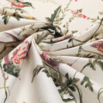 Detail van de Cole & Son-stof Hummingbirds in katoen met een bloem- en kolibriepatroon op licht achtergrond.