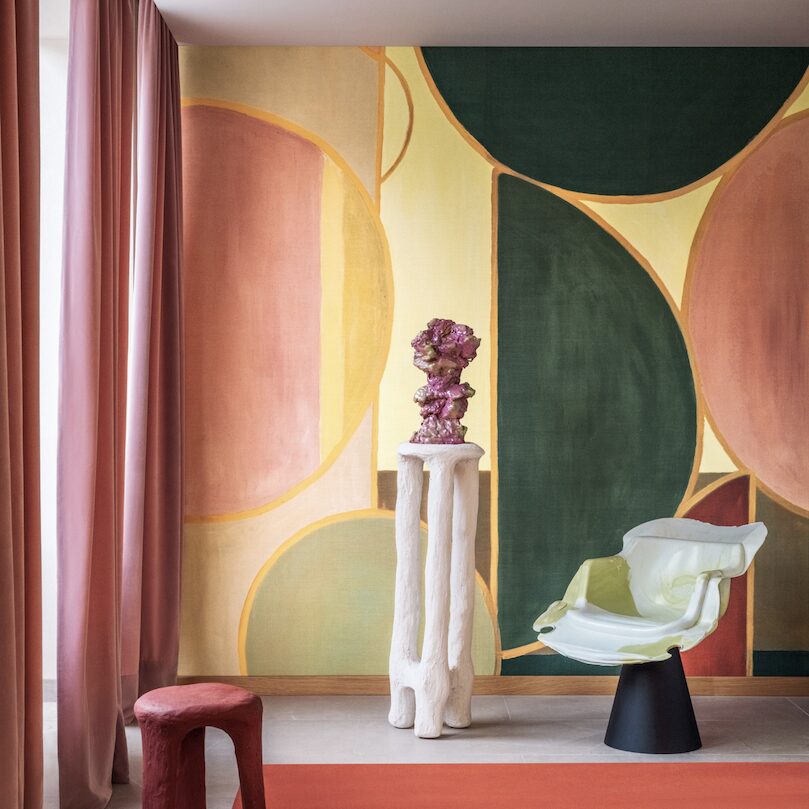 Modern interieur met kleurrijk geometrisch behang uit de collectie ‘Éclats Cosmiques’ van Véronique de Soultrait, met designmeubels en sculpturale decoratie.