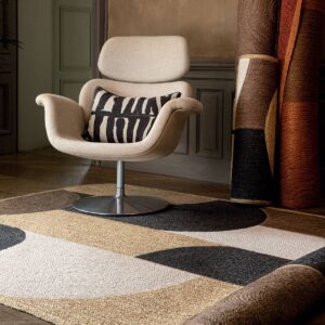 Designstoel met kussen op een Elitis Acapulco vloerkleed in een sfeervol interieur.