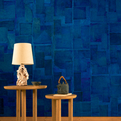 Twee houten bijzettafels met decoratieve objecten staan voor een blauw Elitis Art Paper behang in het ontwerp Amami RM 1035 05.