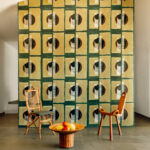 Kamer met Elitis Art Paper behang Izu RM 1030 05, twee designstoelen en een rotan bijzettafel met fruit.