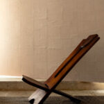 Houten designstoel voor een muur met Elitis Art Paper behang uit de Okinawa RM 1032 01 collectie.