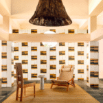 Interieur met Elitis Art Paper behang Okinawa RM 1032 04, houten meubels en een grote hanglamp in een moderne sfeersetting.