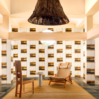 Interieur met Elitis Art Paper behang Okinawa RM 1032 04, houten meubels en een grote hanglamp in een moderne sfeersetting.