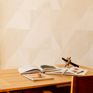Houten bureau met open boeken en decoratieve voorwerpen voor een muur met Elitis Art Paper behang Tokara RM 1034 01.