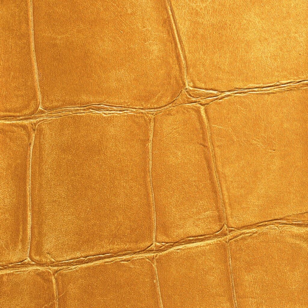 Close-up van een gouden krokodillenleren textuur uit de Elitis Big Croco metal VP 951 92 collectie.