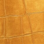 Close-up van een gouden krokodillenleren textuur uit de Elitis Big Croco metal VP 951 92 collectie.