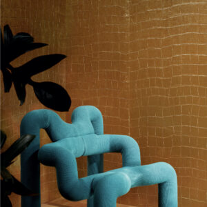 Turquoise designstoel voor een goudkleurige Elitis Big Croco metallic wandbekleding.