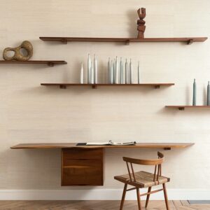 Houten bureau met bijpassende stoel tegen een muur met Elitis Ecrin behang en houten wandplanken met decoratieve objecten.