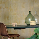 Moderne eethoek met houten stoel, glazen vazen en keramiek op een tafel voor Elitis Eldorado behang met goudgele textuur.
