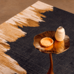 Detail van het Elitis Emile TA 135 82 02 vloerkleed met een goudkleurig bijzettafeltje en keramische decoraties erop.