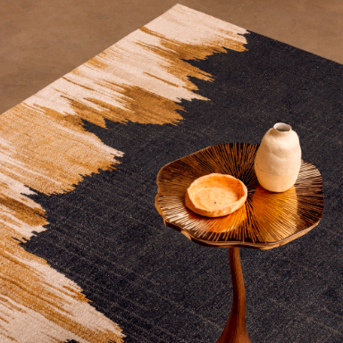 Detail van het Elitis Emile TA 135 82 02 vloerkleed met een goudkleurig bijzettafeltje en keramische decoraties erop.