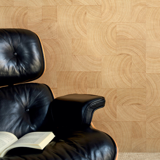 Zwarte leren loungefauteuil met open boek ervoor, tegen een wand met Elitis Empreintes RM 1040 15 behang uit de Marqueteries collectie.