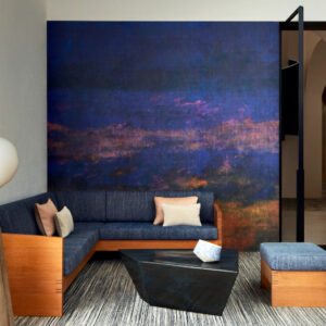 Sfeervolle woonkamer met Elitis Eternite VP 965 01 atelier d'artiste behang in diepe blauwtinten en een moderne zitbank met houten elementen.