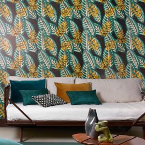 Woonkamer met Elitis Flower Power Alocasia TP 302 03 behang met tropisch bladmotief en een bank met gekleurde kussens.
