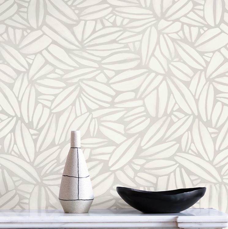 Beige Elitis Flower Power Succulente TP 301 01 behang met abstract bladpatroon, met een vaas en zwarte schaal op een wit oppervlak.