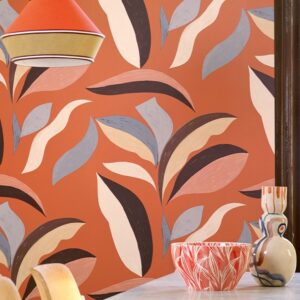 Oranje Elitis Flower Power-behang met abstracte botanische vormen in lichte en donkere tinten, gecombineerd met kleurrijke keramieken decorstukken op de voorgrond.