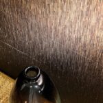 Glinsterend metallic Elitis Formentera Alegria VP 719 01 behang met verticale structuur, naast een donkere glanzende vaas.